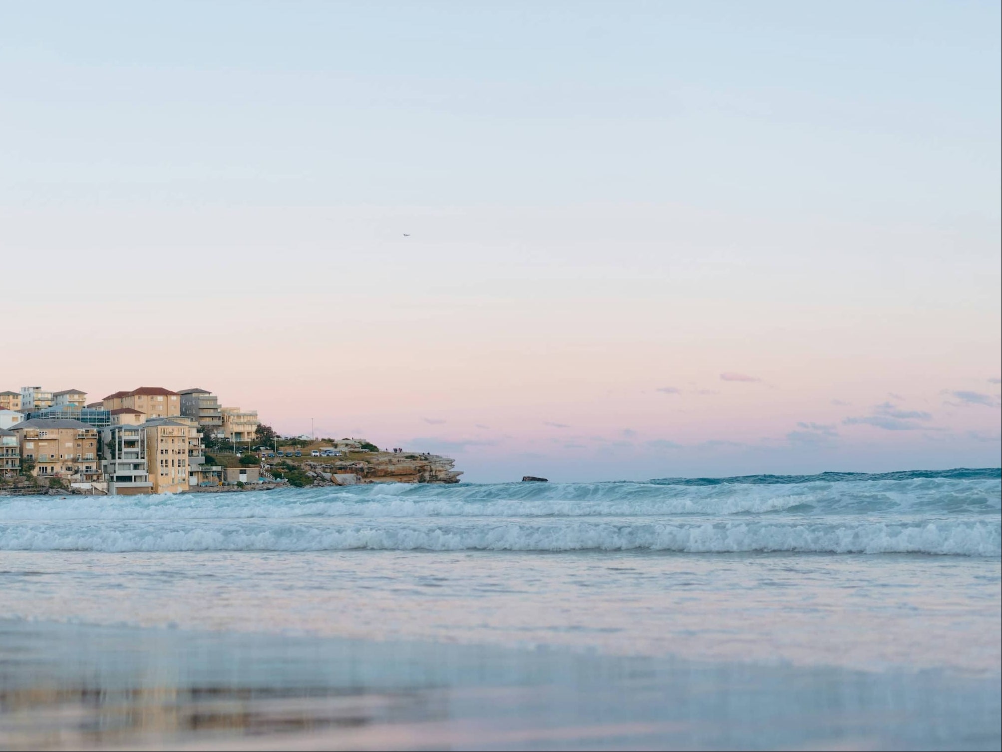 Coastal town with houses along a beach at sunset.